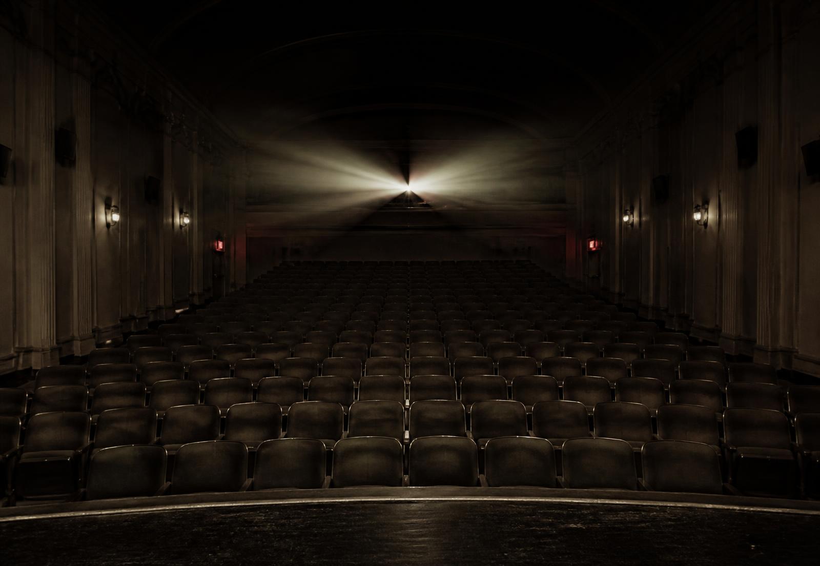 An empty cinema auditorium with a single projector beam